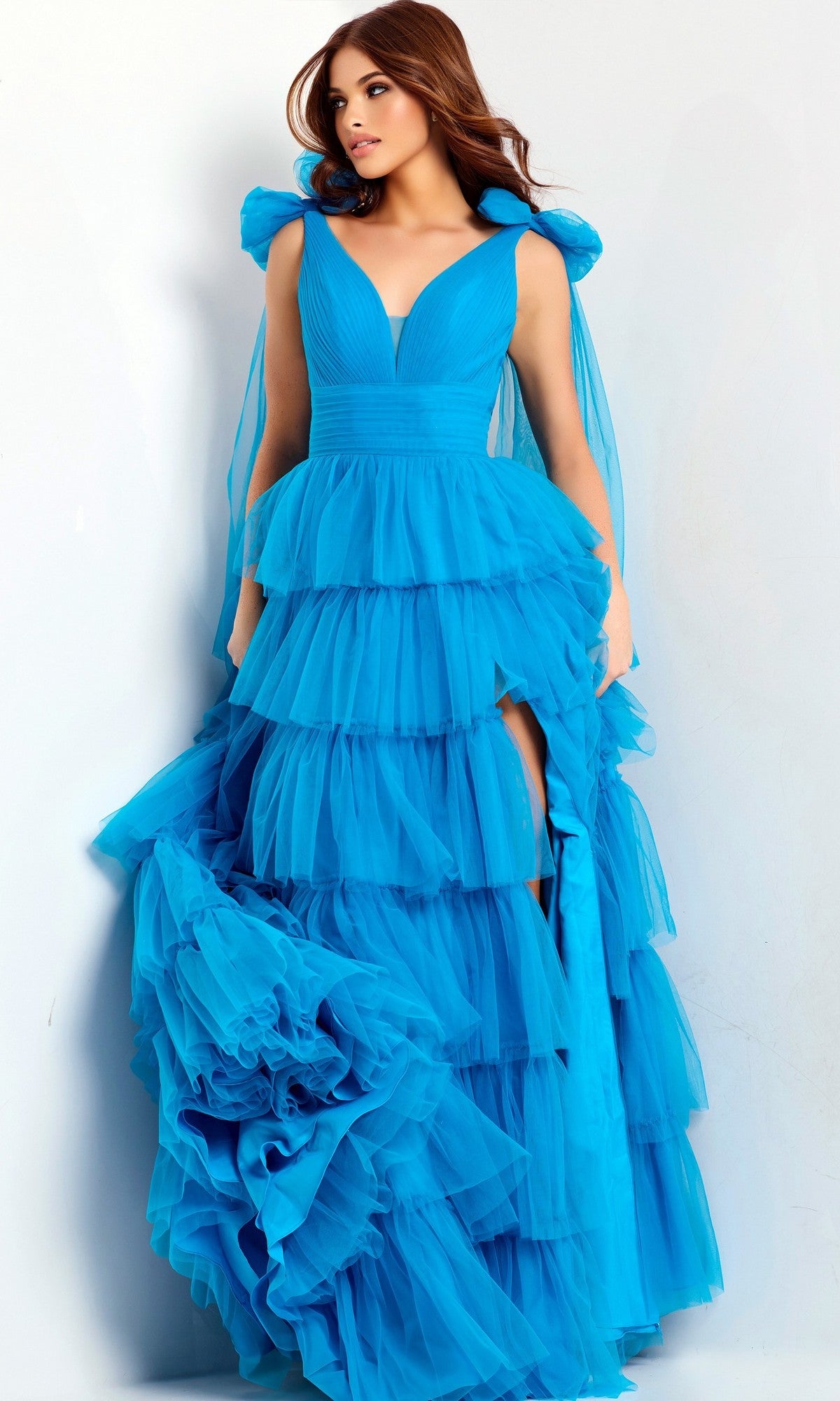Woman wearing a turquoise Jovani 48288 long prom dress with a sleeveless bodice, tiered ruffle skirt, layered tulle, and high slit, standing against a plain light background.